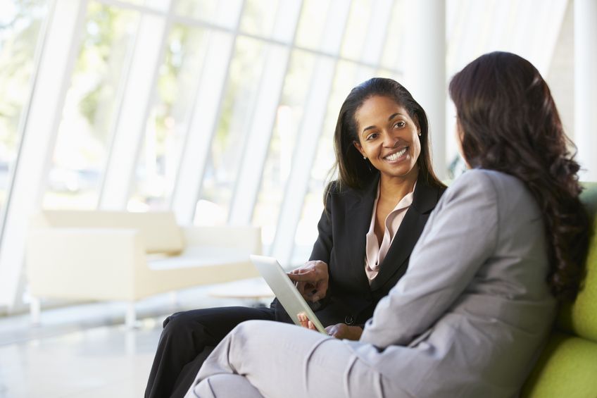 A mentor and mentee with digital tablet sitting in a modern office.