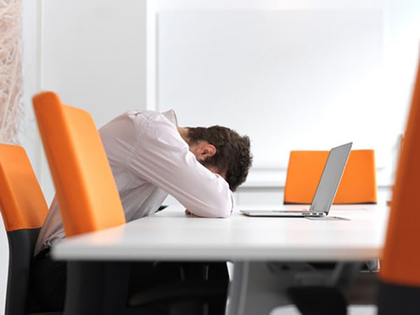 A frustrated and stressed out business man sitting alone at office meeting room and working on laptop computer.