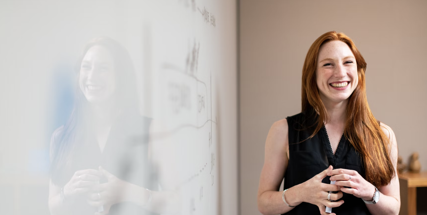 Woman smiling in front of a white board after achieving career goals.