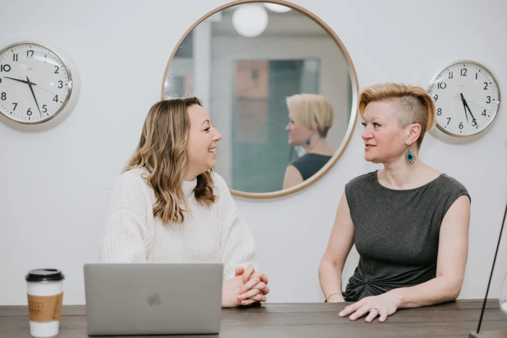 Two women at a table discussing neurodiversity in the workplace.