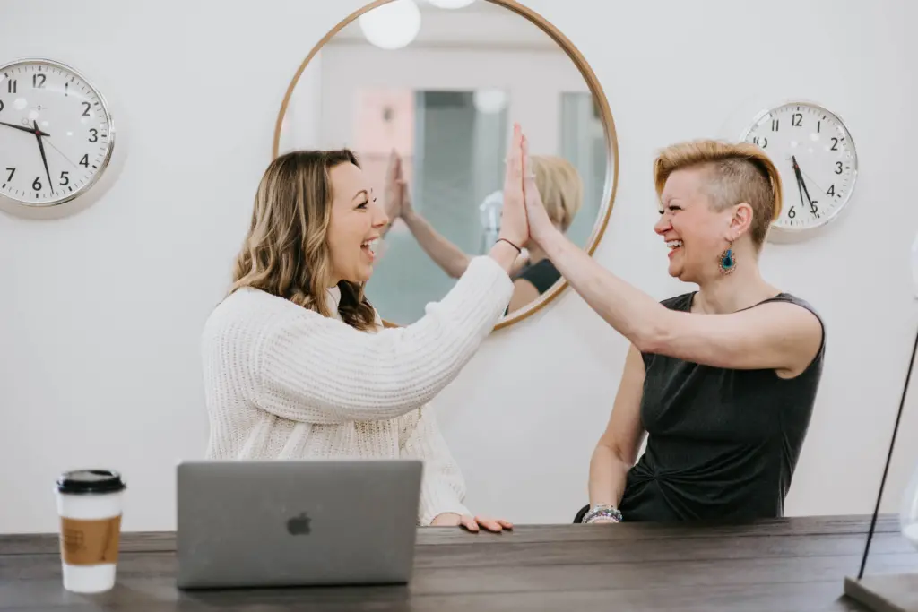 Two women in an office giving a high give as a way to thank you to mentors.