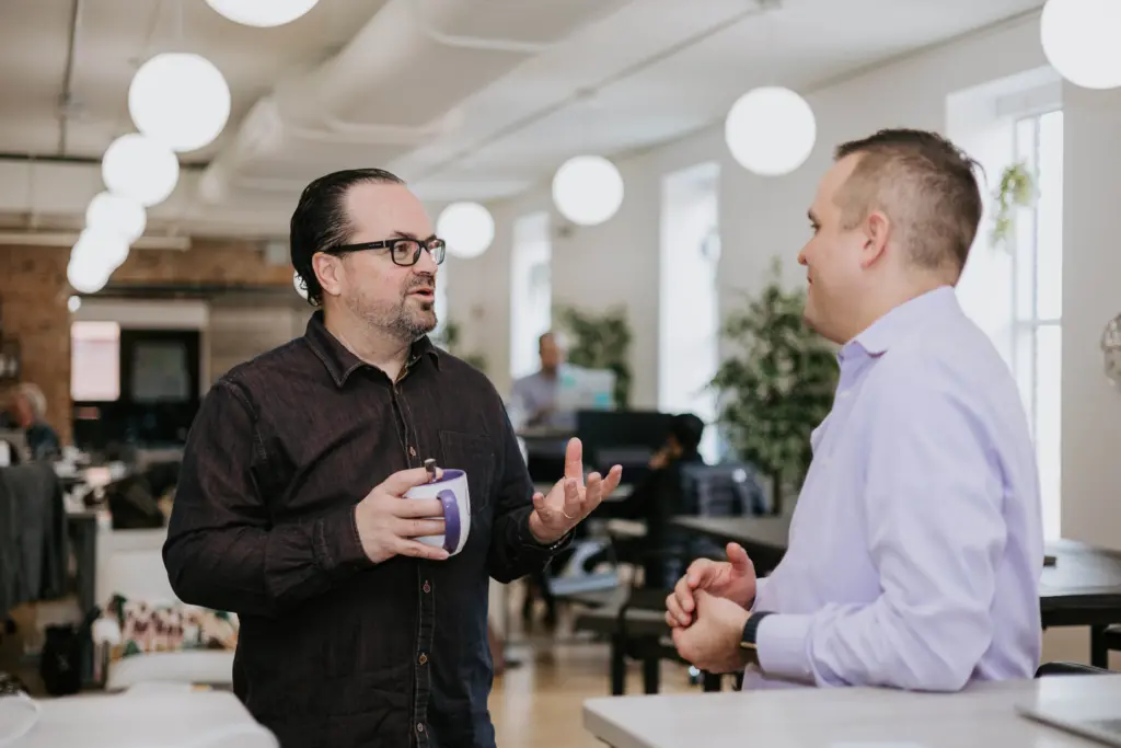 Two men in an office talking, depicting a positive mentoring culture.