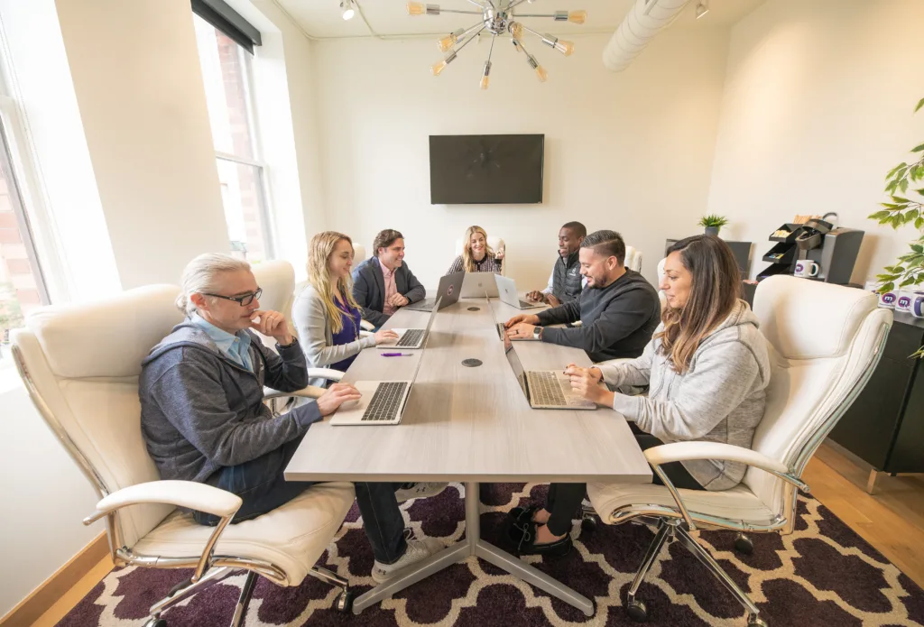 A team meeting in an office room speaking on the definition of leadership. 