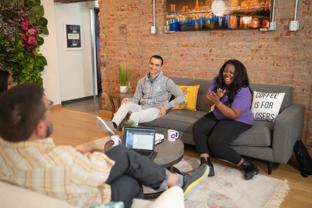 Group of employees engaging in discussion on a couch during reverse mentoring engagement.