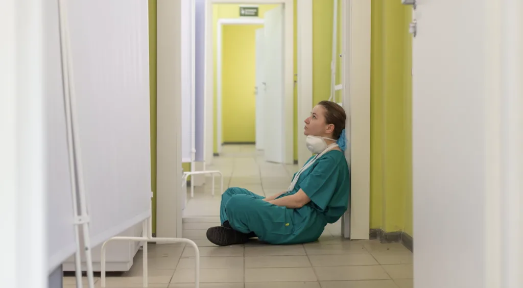 Tired nurse sitting on the floor turnover