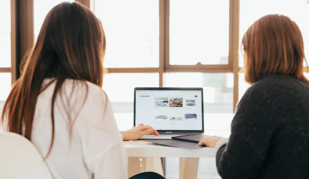 Two women sitting in front of a computer in a peer mentoring relationship.