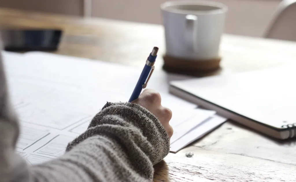 Woman writing on a paper for mentoring goals.