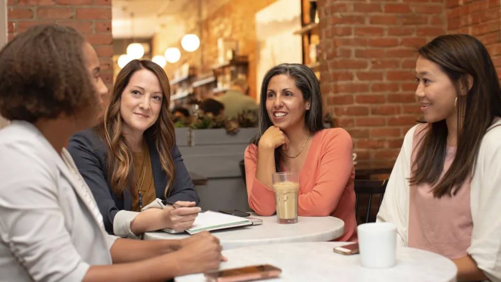 Four women in a mentoring relationship engaged in a mentoring activity of drinking coffee. 